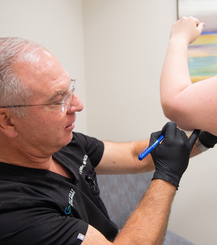 Doctor marking the arm of his client for the arm lift procedure