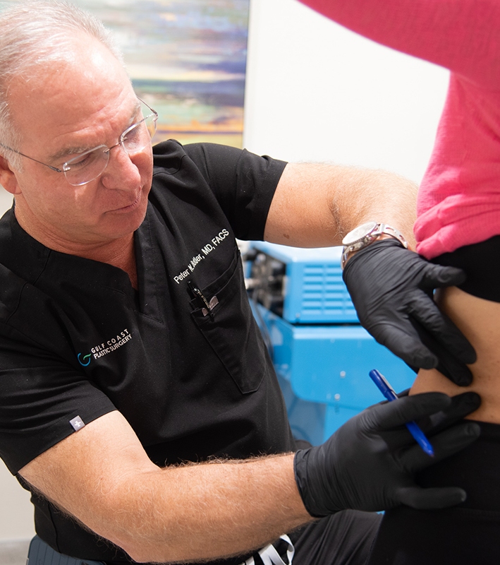 Dr. Butler with black gloves holding the belly of his patient for liposuction